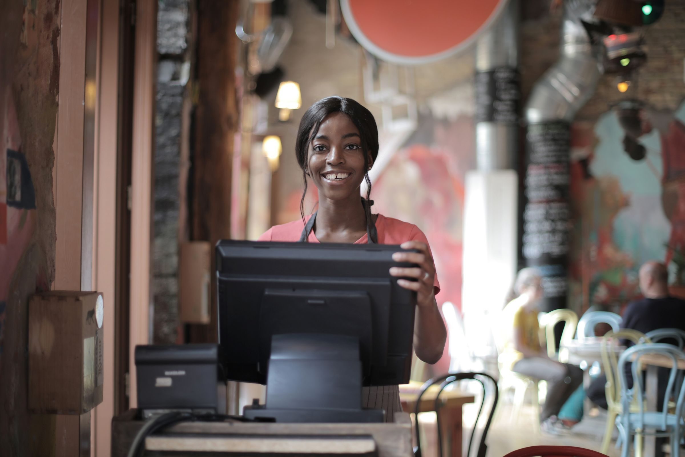 A smiling café worker at the counter till