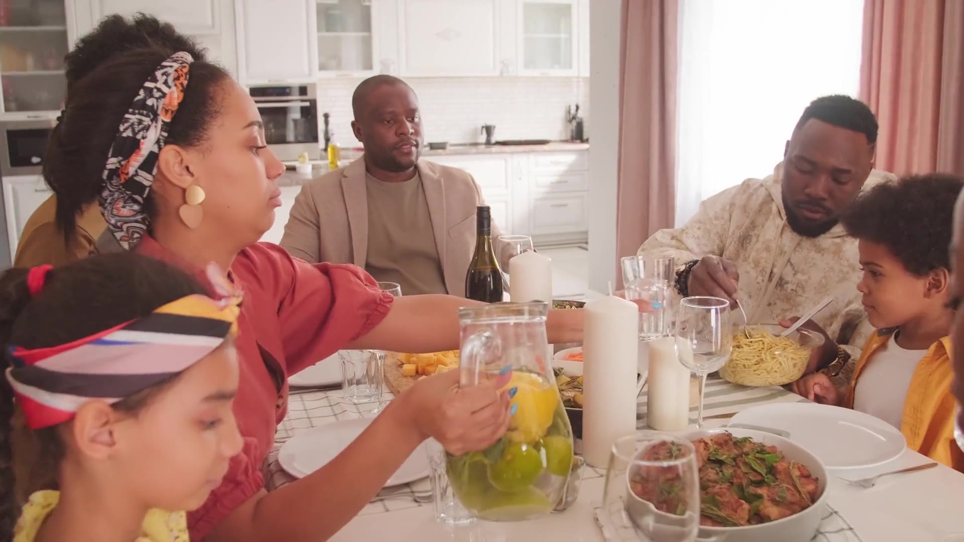 Family and friends sharing dinner around a long table, laughing and passing dishes