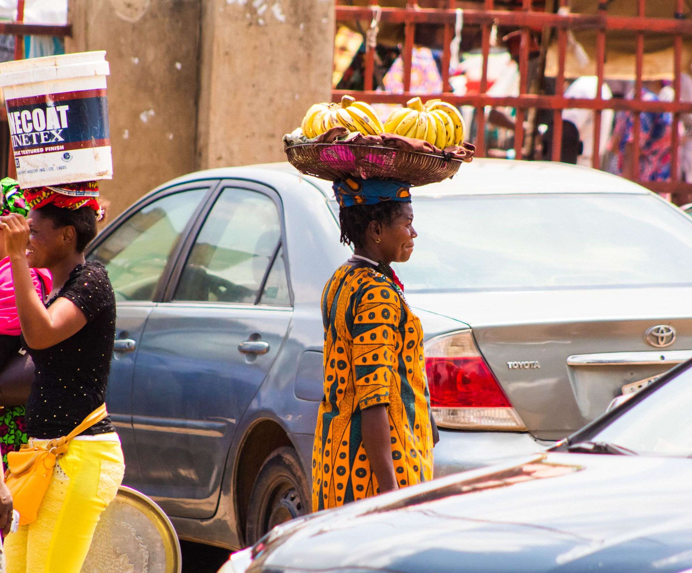 Women carrying fruit to sell through a busy market street