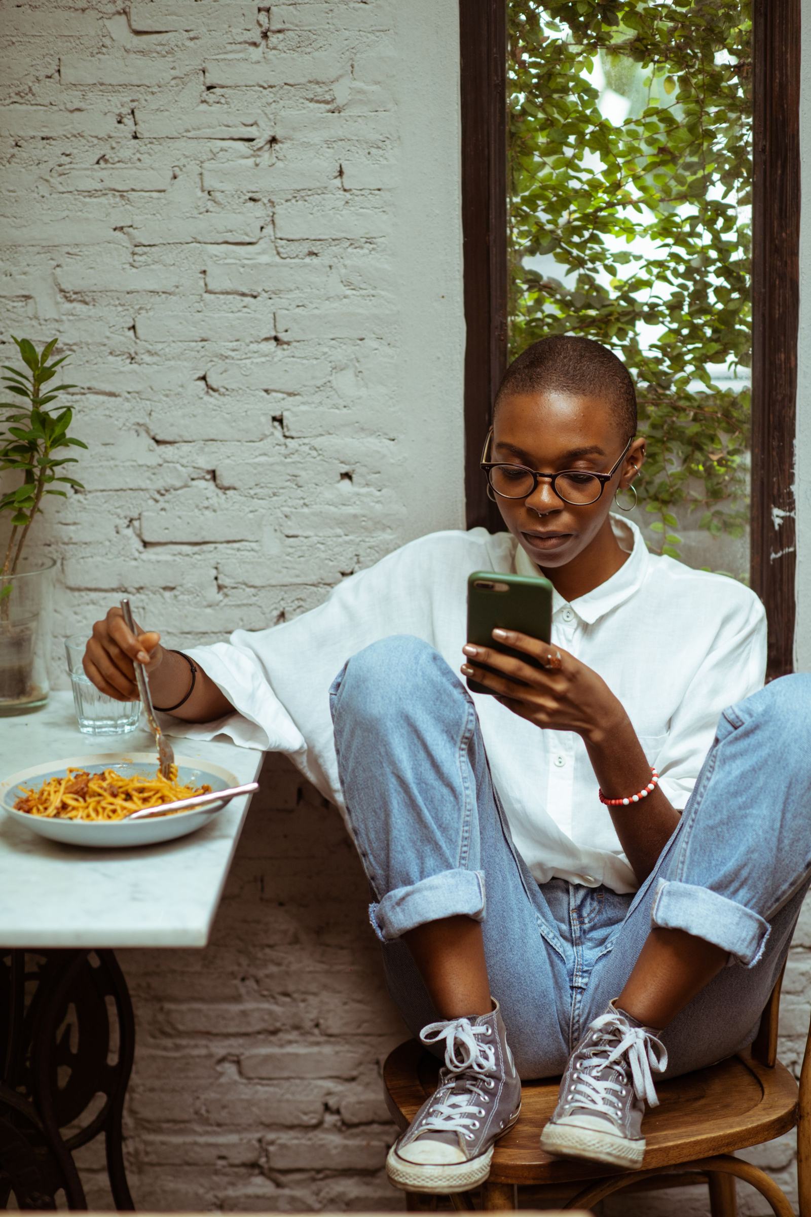 A woman eating at a café, smiling at her phone