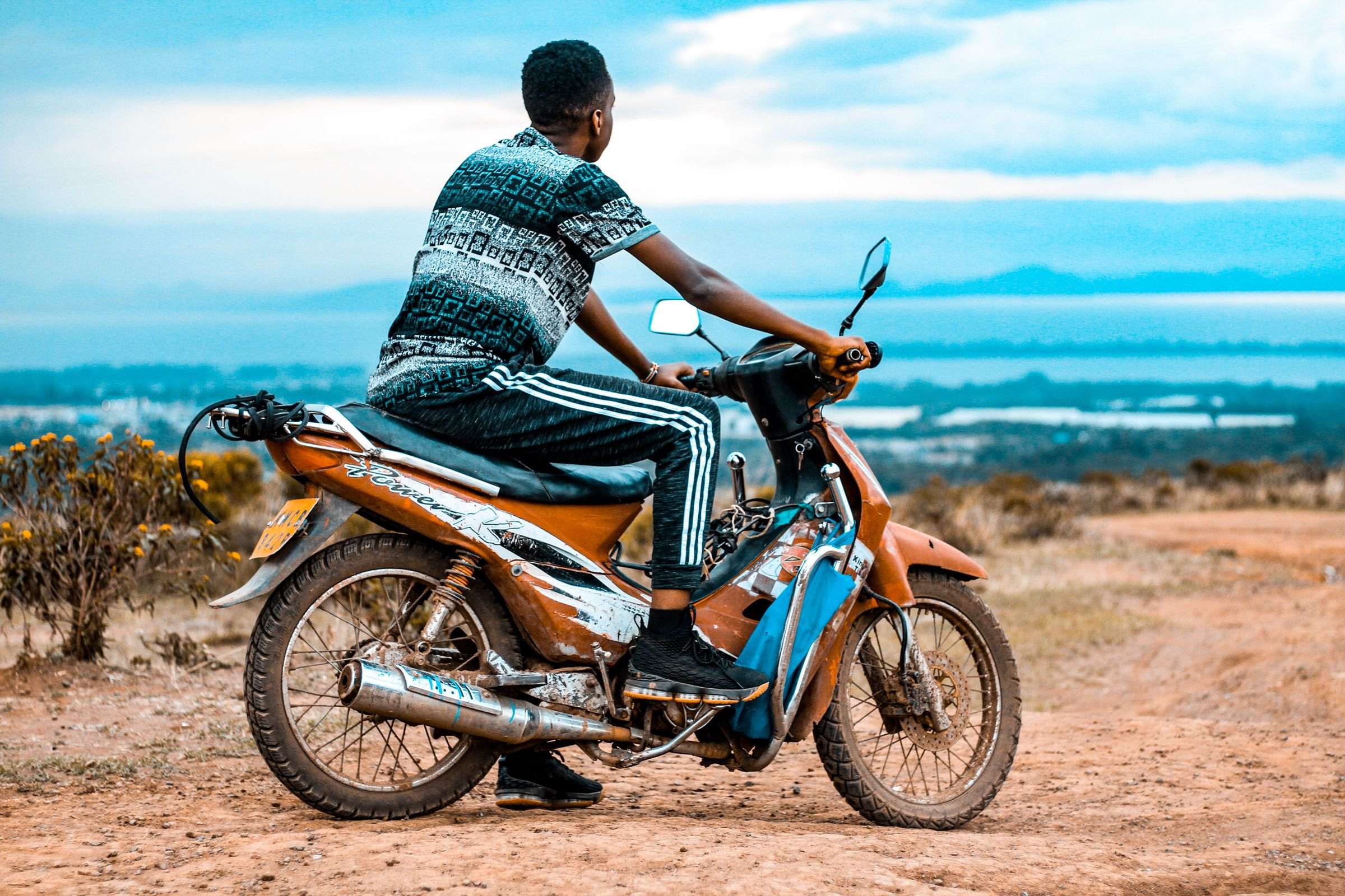 A motorbike rider pausing on a hilltop above a lake